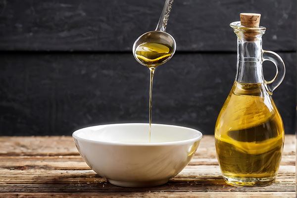 pouring olive oil from a glass bottle into a bowl