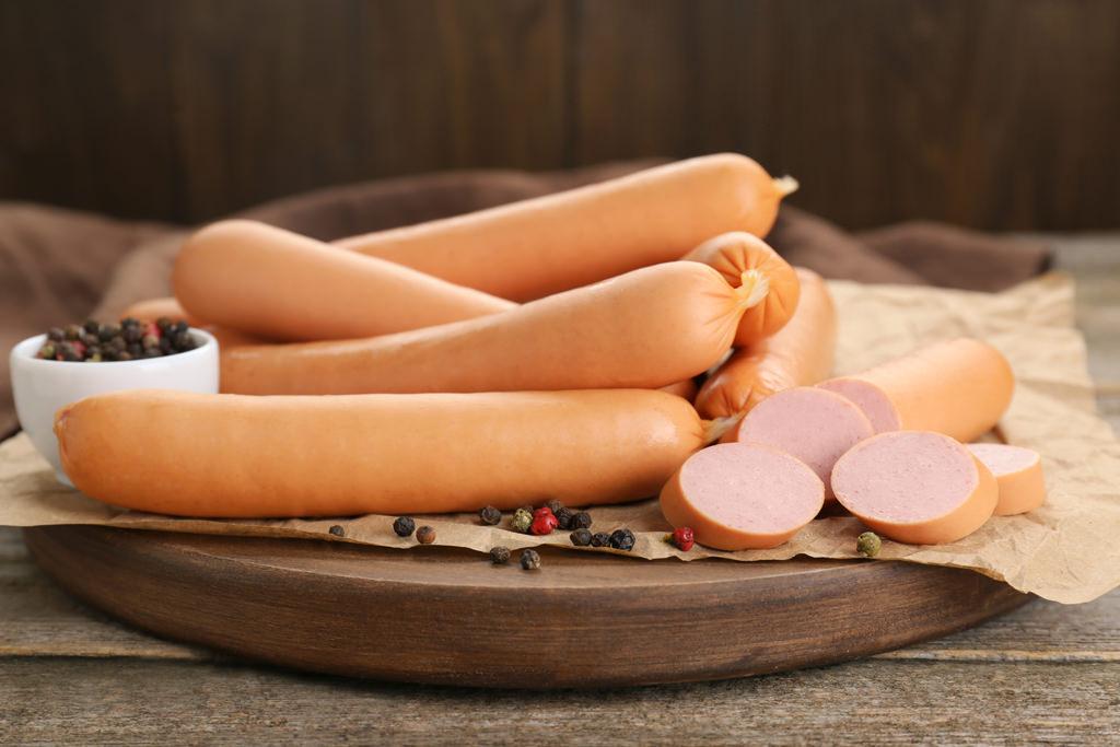 tasty sausages and peppercorns on wooden table, closeup. meat pr